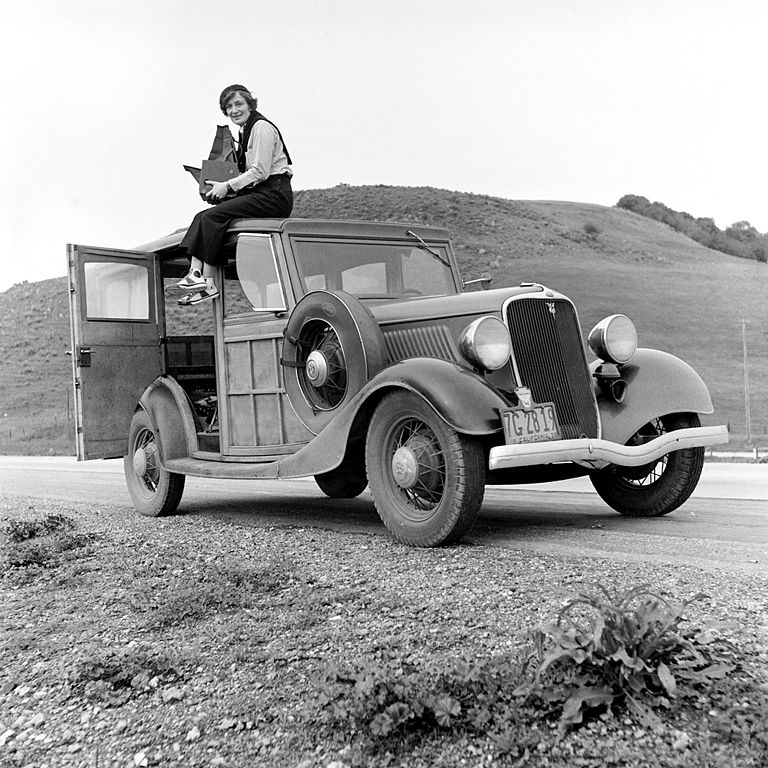 Dorothea Lange sitting on a car