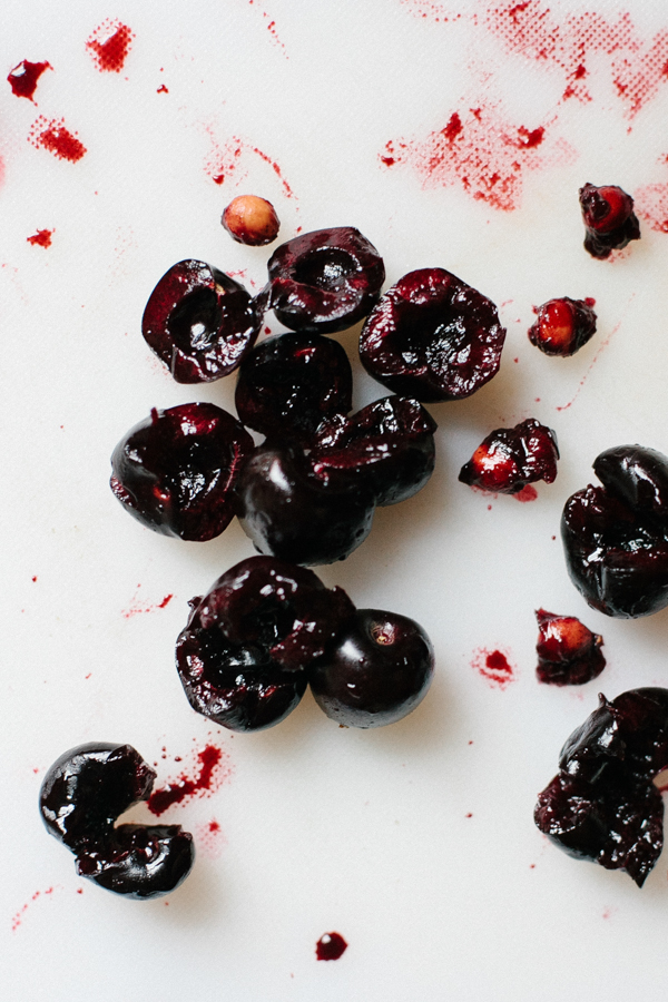 mashed and cut cherries on a cutting board