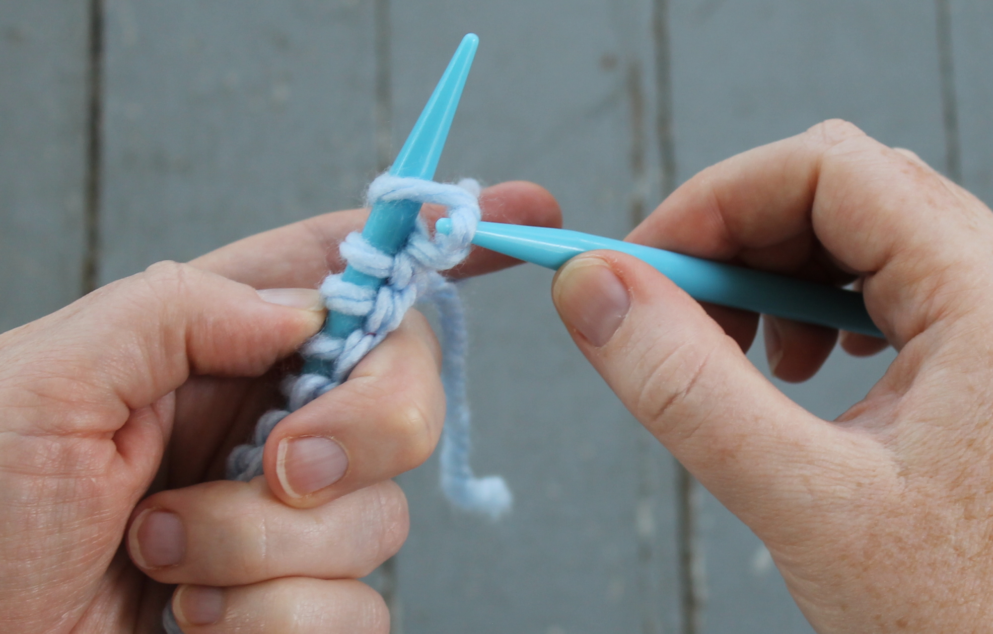Pulling yarn through to make a knit stitch