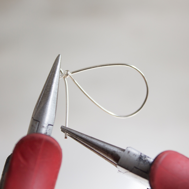 Hold the smaller loop firmly with your flat-nose pliers