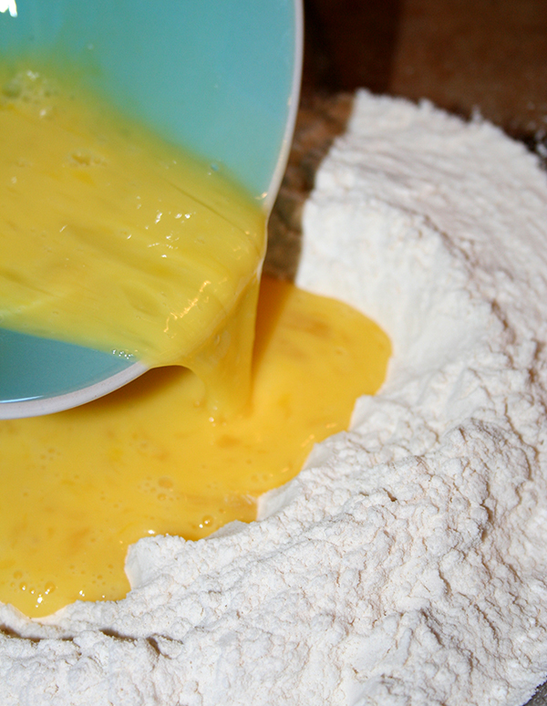 Pour beaten eggs into a well of flour to make easy handmade pasta.