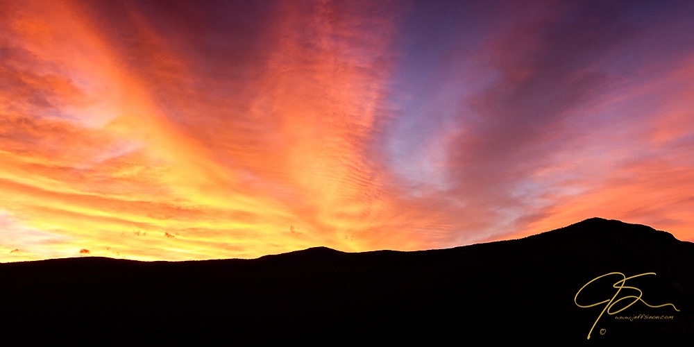 Fiery sky over the black silhouette of mountains.