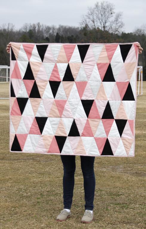 Woman holding a pink triangle baby quilt