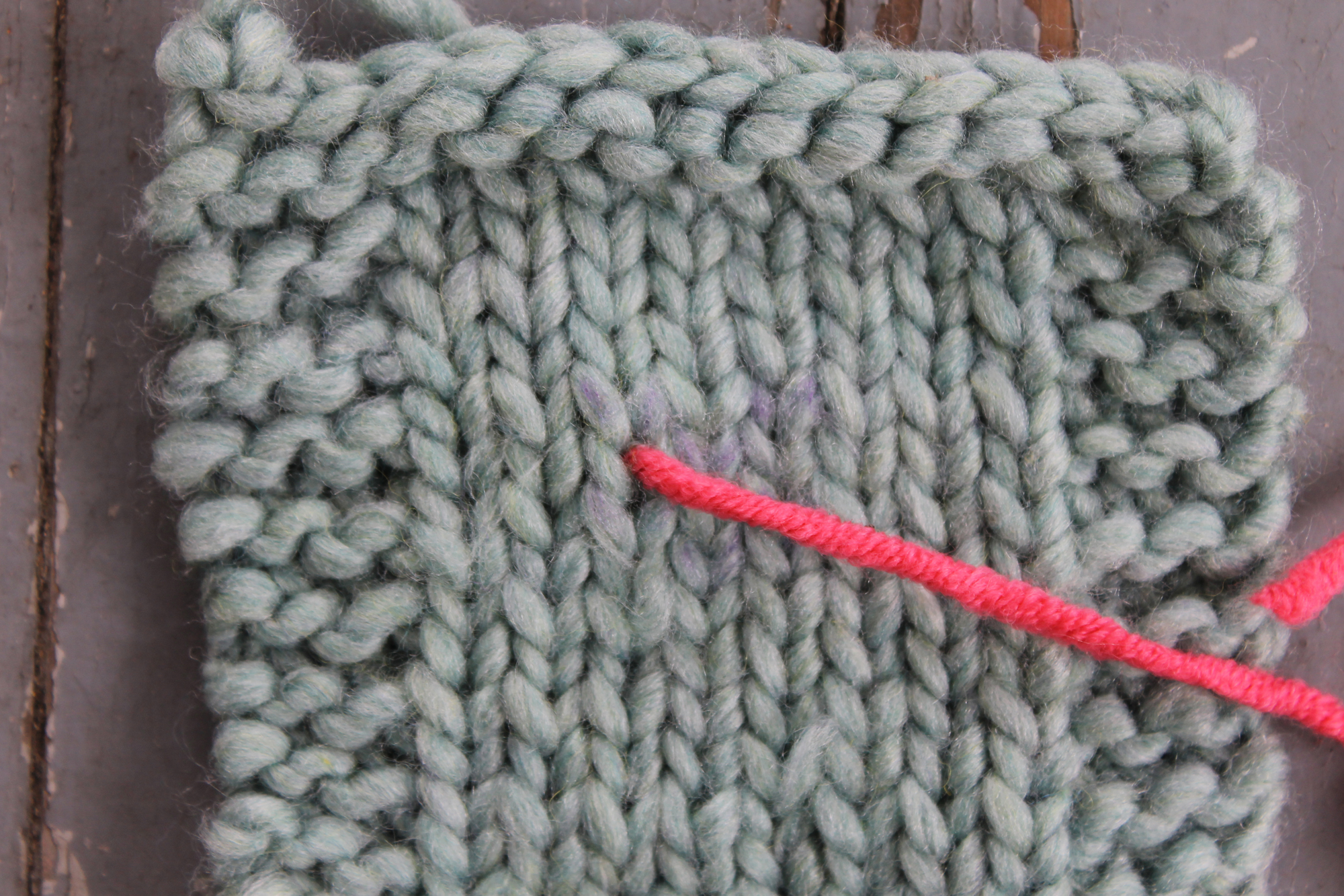 Inserting the tapestry needle at the bottom of the V for duplicate stitch