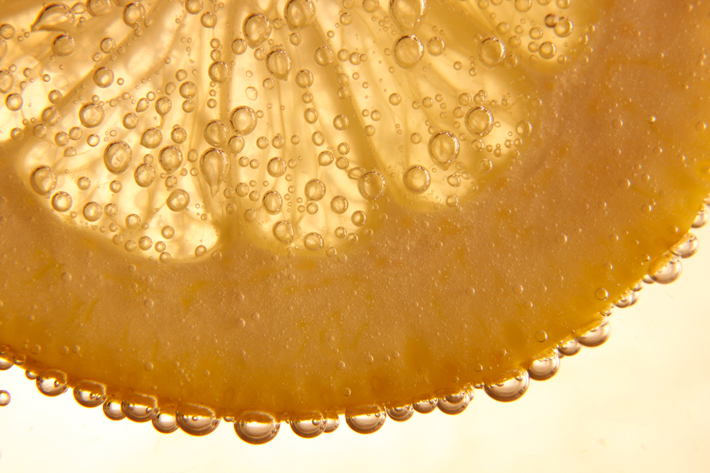 Macro orange slice with fizzy bubbles photographed with a close-up lens on a tripod