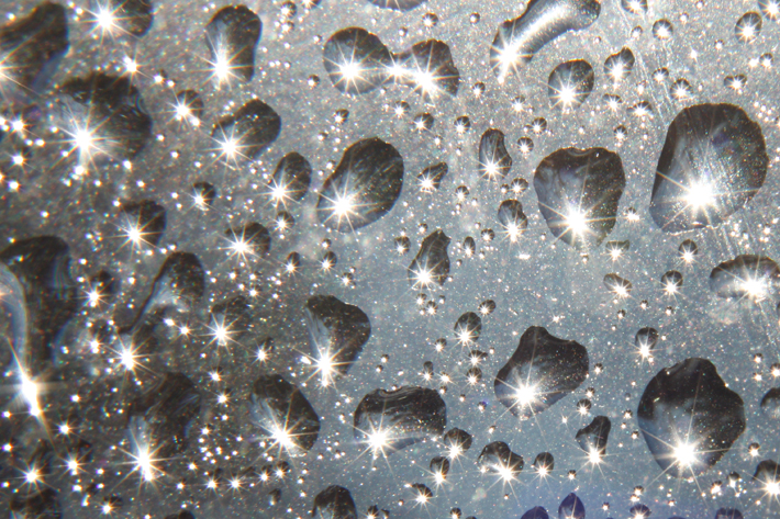 Macro water droplets with sun flare photographed with a close-up lens
