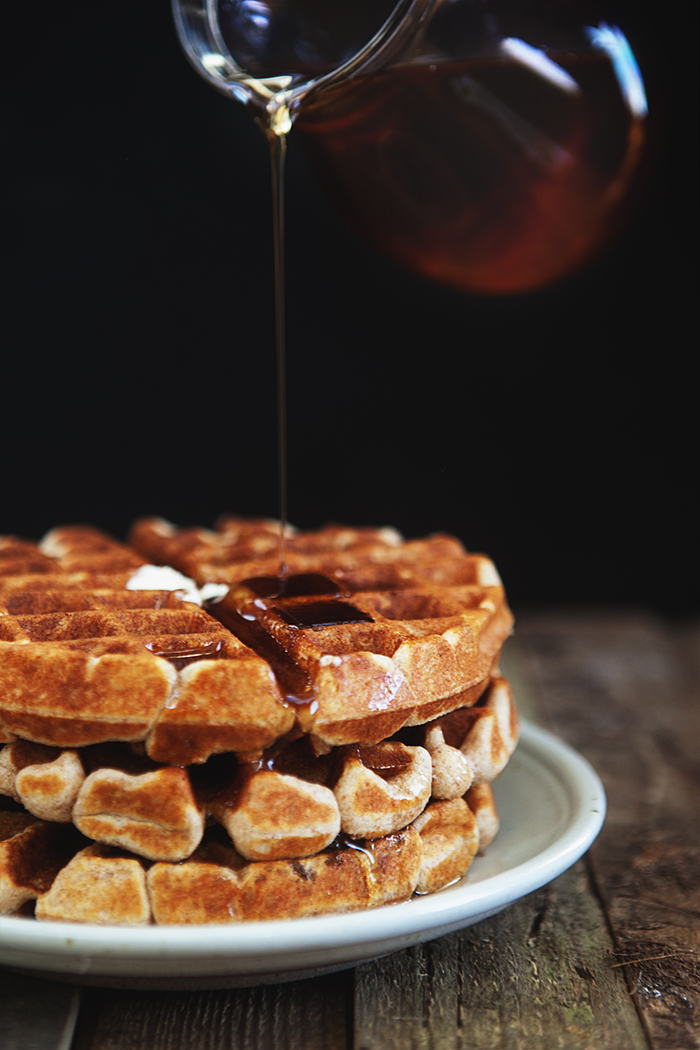 Pouring homemade maple syrup over a plate of fresh waffles