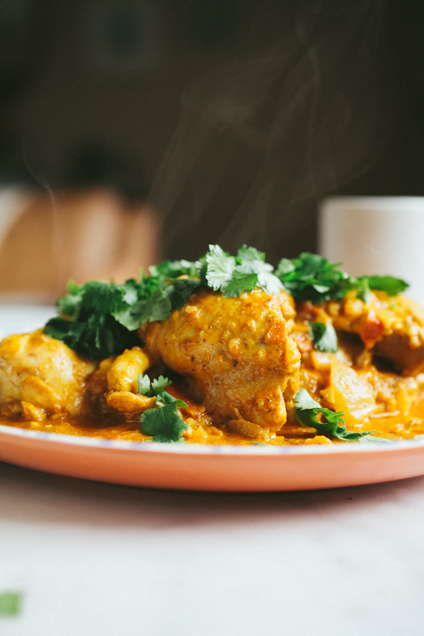 Steaming plate of butter chicken topped with fresh cilantro