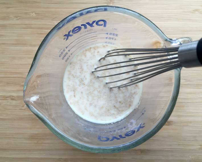 milk, sugar, yeast in a measuring up with a whisk