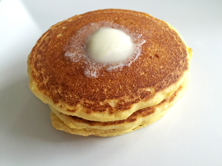 A delicious stack of cornbread pancakes with a pat of melty butter — yum!