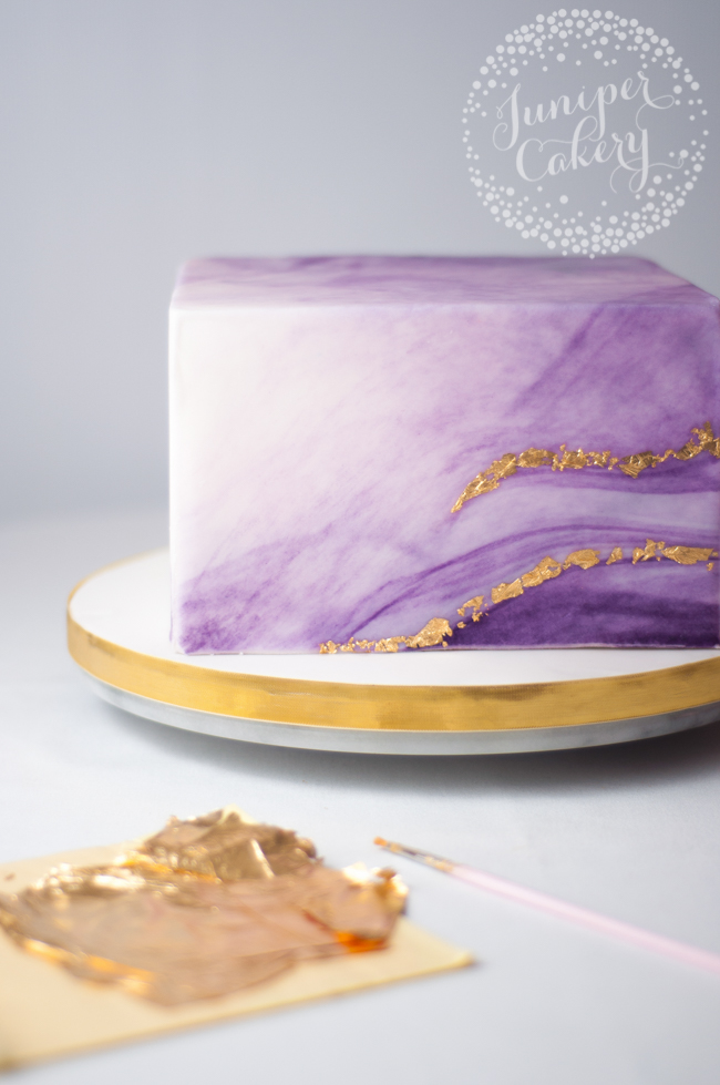 adding gold flakes to purple marbled cake