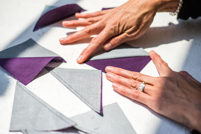 finger pressing a gray and purple half square triangle