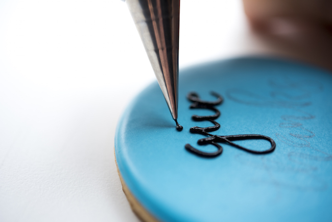 Piping the word give on a cookie