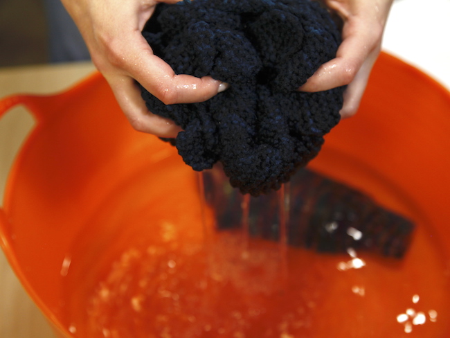 Washing navy sweater in an orange tub