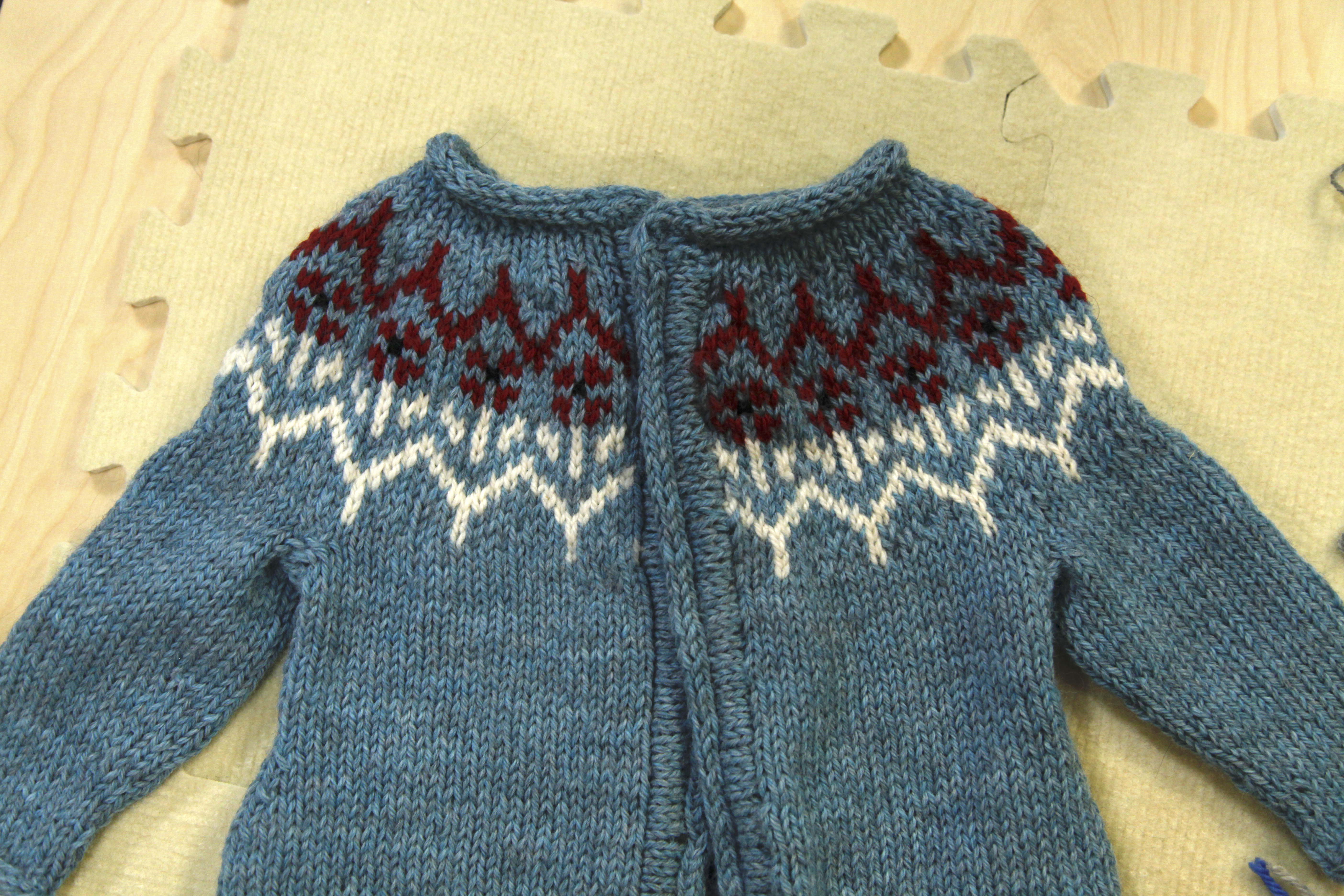 Blocking a blue yoke knitted sweater on tan mats