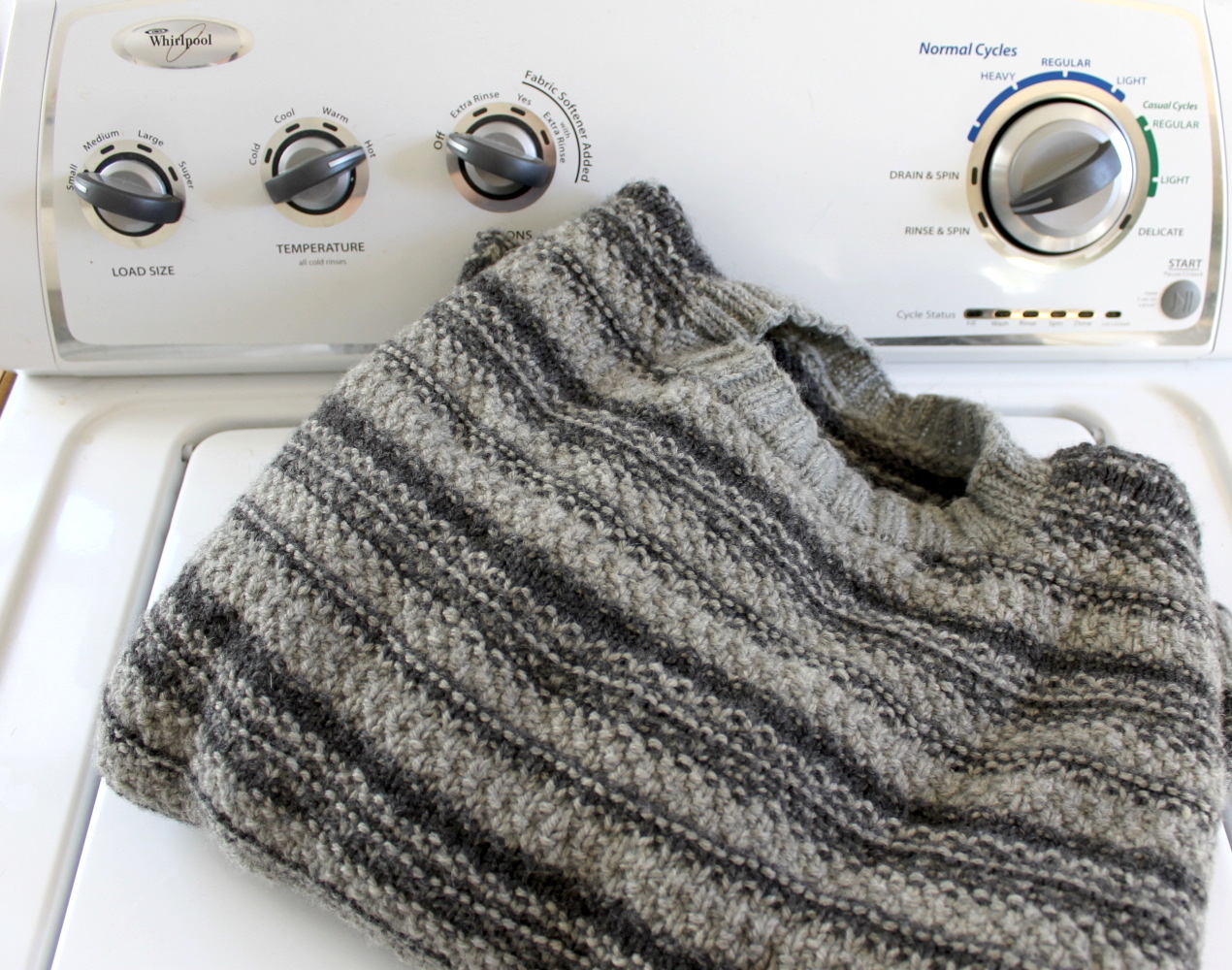 Gray striped knit sweater on top of a washing machine