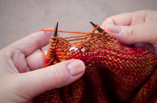 Person's Hands Knitting Orange Garmet
