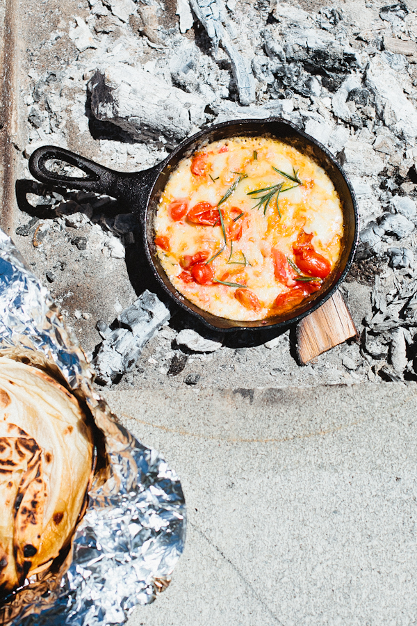 Eggs, Tomatoes and Herbs in Cast Iron Skillet Over Campfire