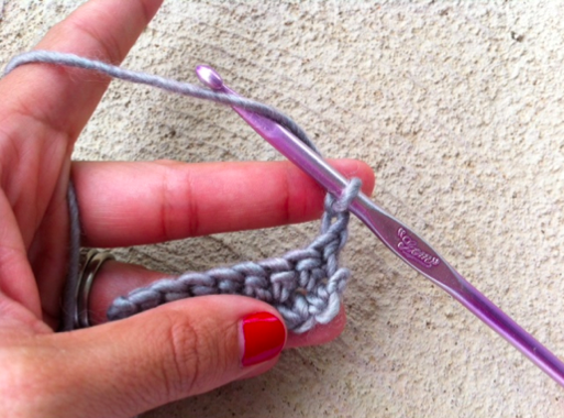 Woman's Hands and Yarn Wrapped Around Purple Crochet Hook