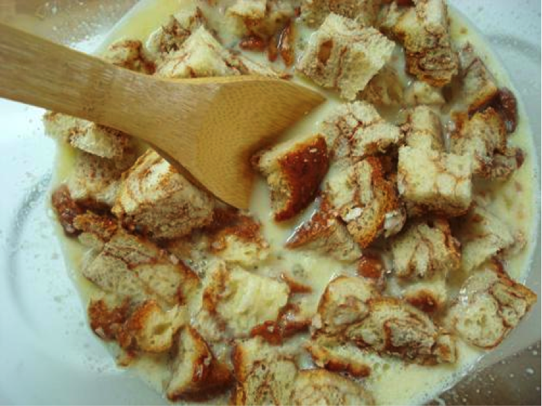 Wooden Spoon Stirring Bread Cubes with Sugary Sauce