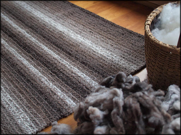 Striped Grey-Toned Knit Rug Next to Basket and Yarn