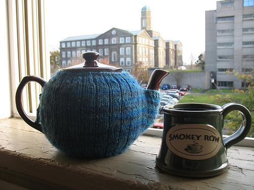 Tea Pot Covered in Knit Mitten, Sitting Next to Mug