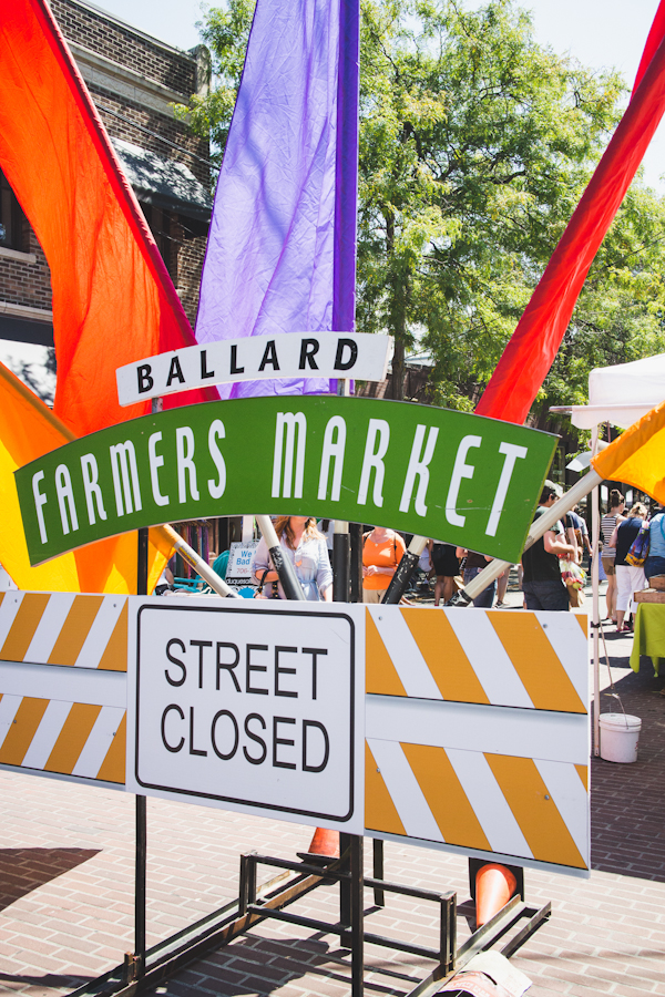 Entrance to Farmers Market with Colorful Flags and Large Sign