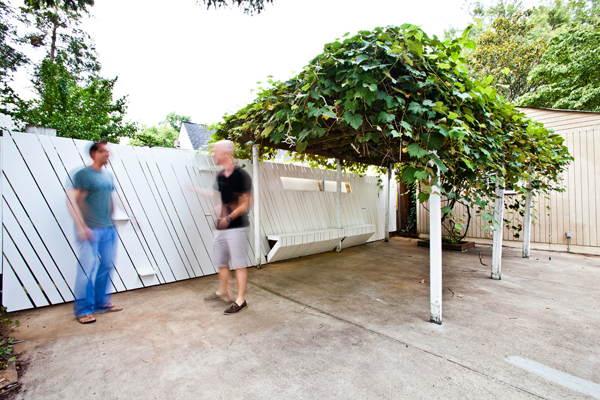 Shot of Two Blurry Men Standing Against a White Fence