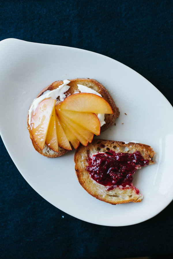 Two Slices of Toasted Bread, One Topped with Peaches, One with Jam 