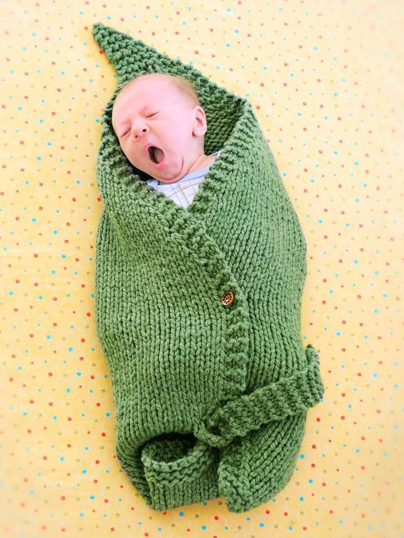 Yawning baby wrapped in green baby blanket