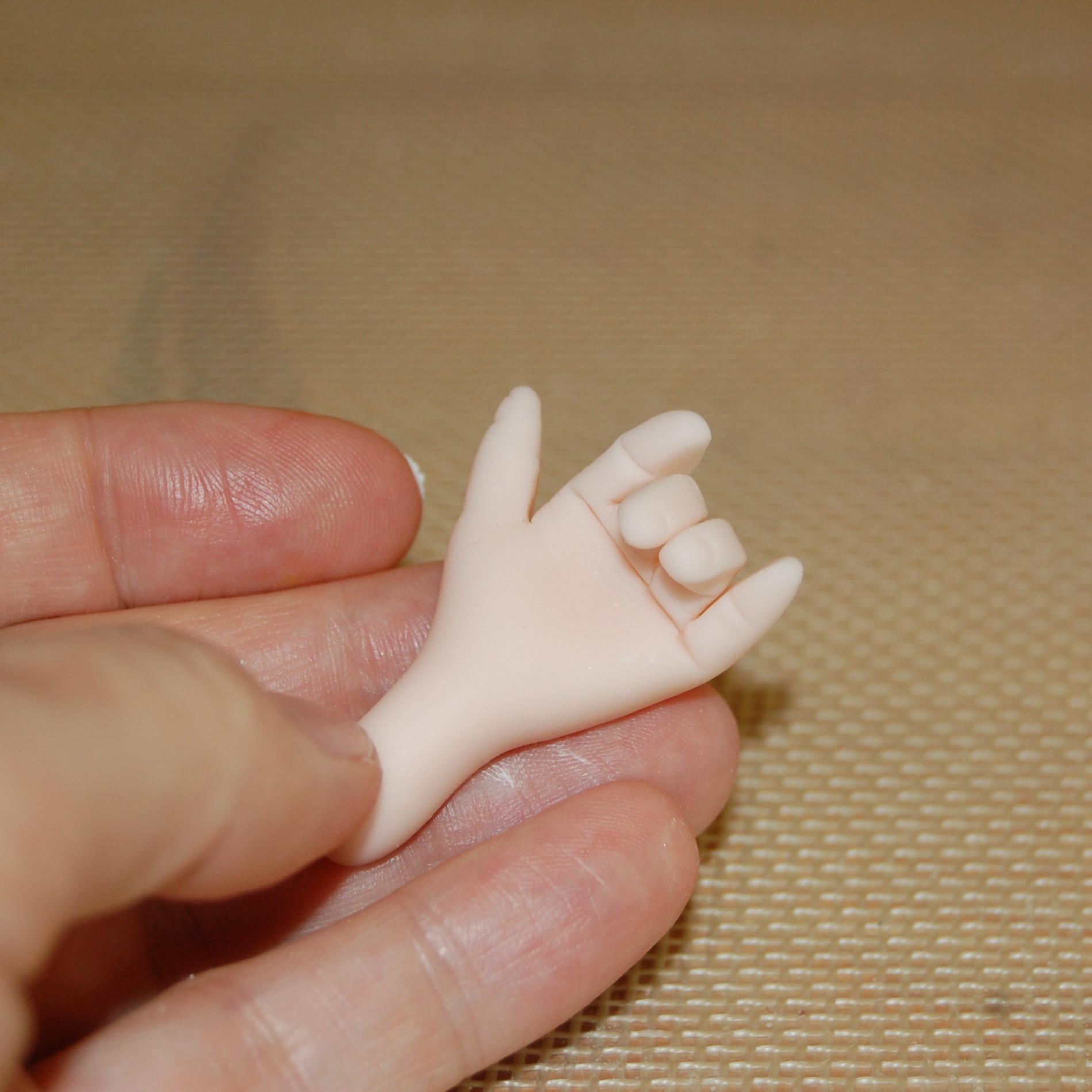 Decorator's Fingers Holding Up Completed Fondant Hand 