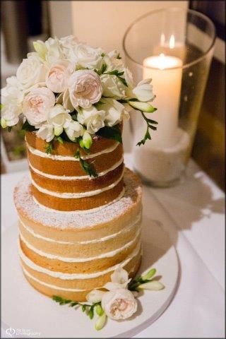 Naked Cake Topped with White Flowers, Next to Candle