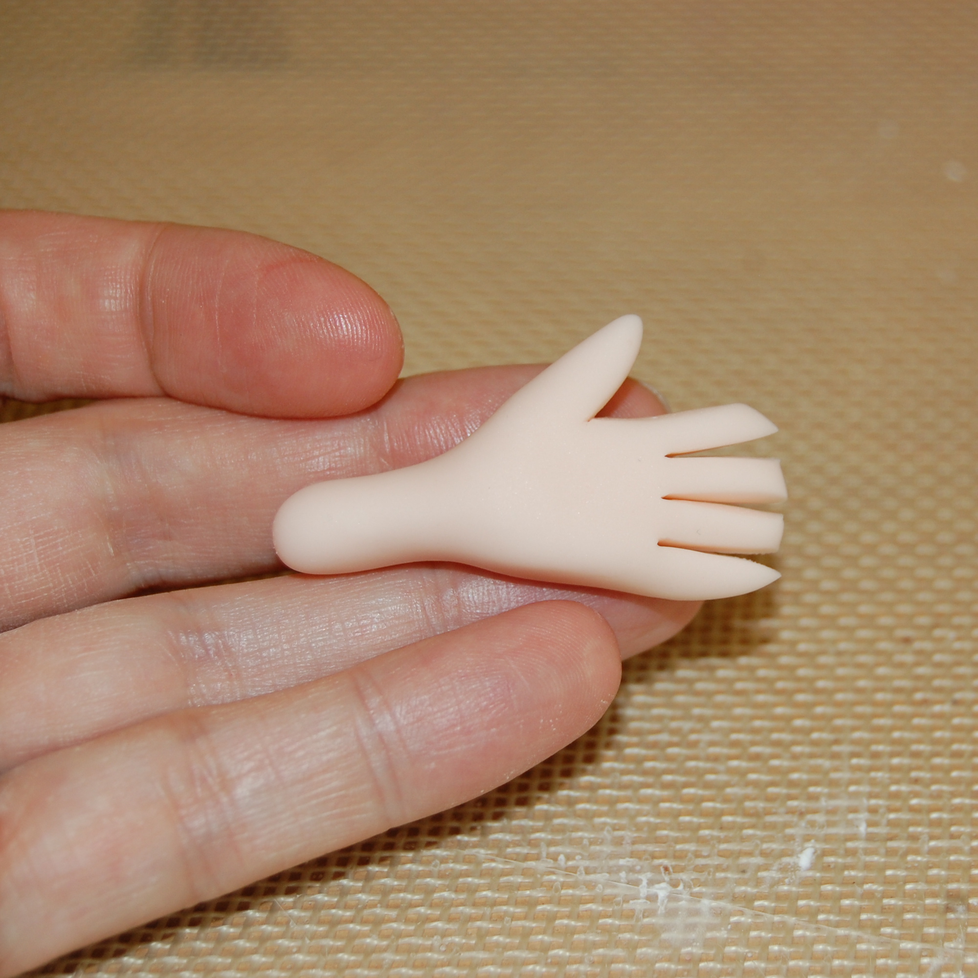 Close Up on Hand Holding Same Piece of Fondant, Now with Fingers