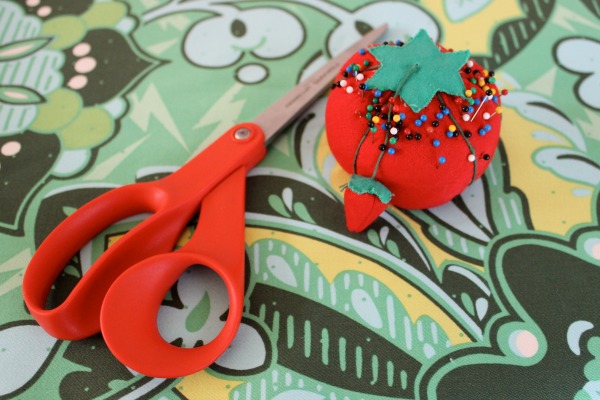 Scissors Laying Next to Pin Cushion on Patterned Table