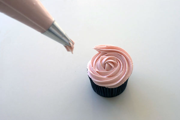 Finishing Putting Pink Icing on Cupcake