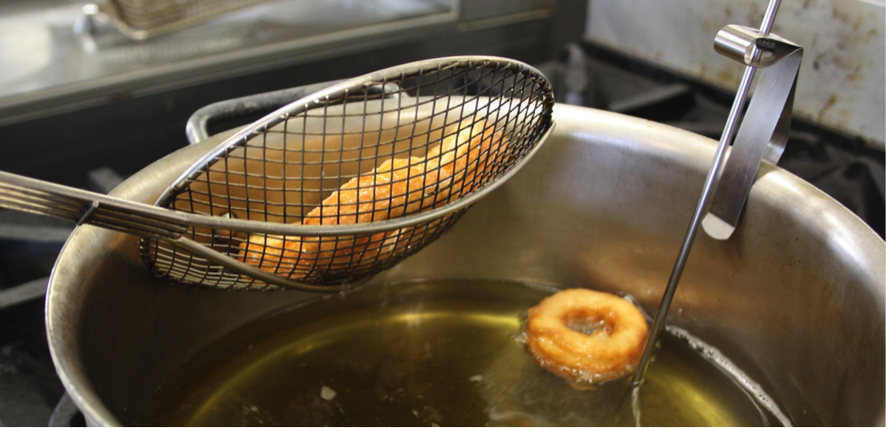 Dough Being Lifted and Strained from Oil in Pan 