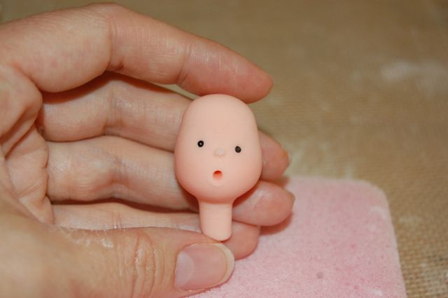 Hand Holding Fondant Baby Face with Little Round Mouth