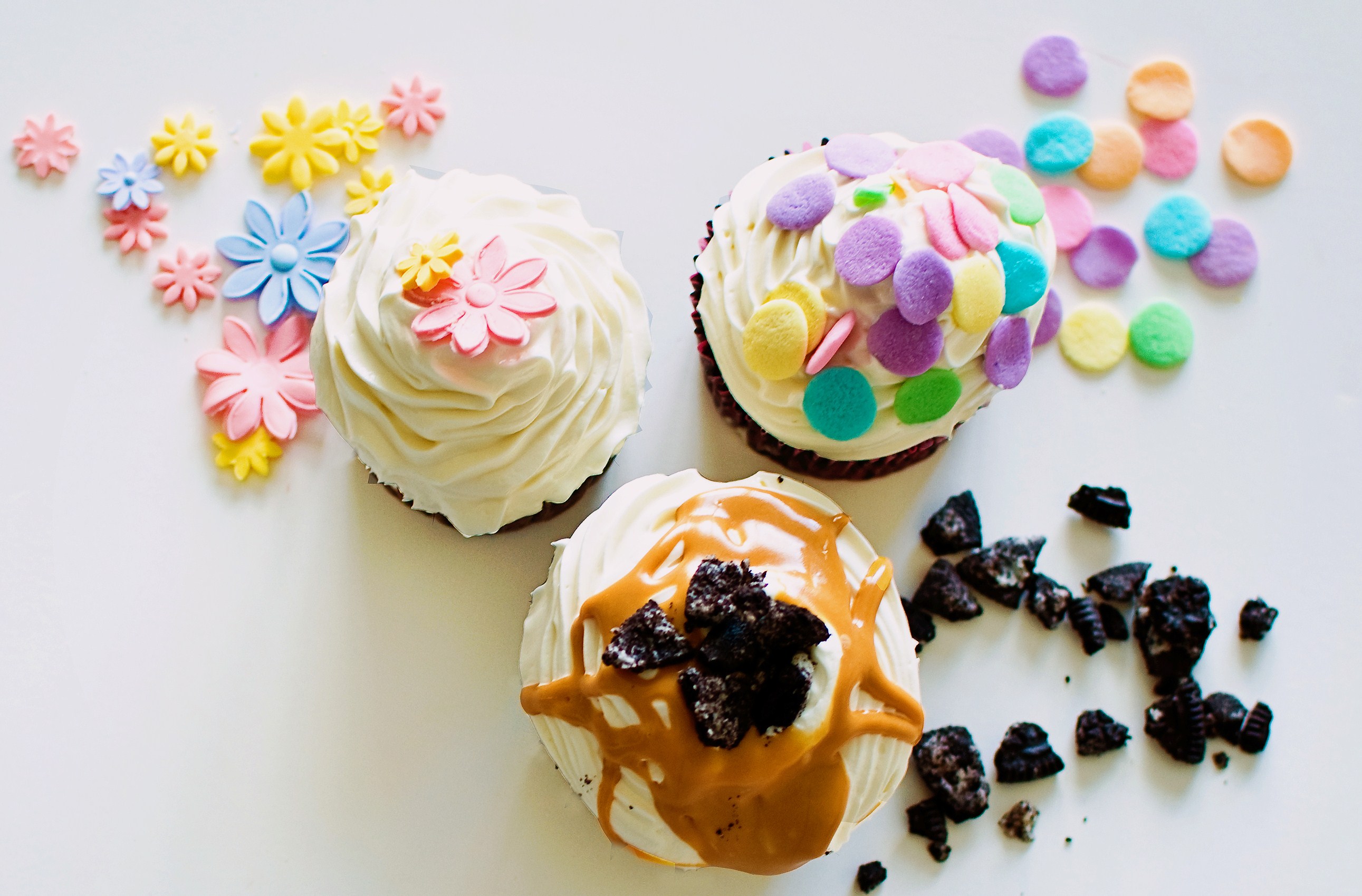 Different Cupcakes Next to An Array of Sprinkles