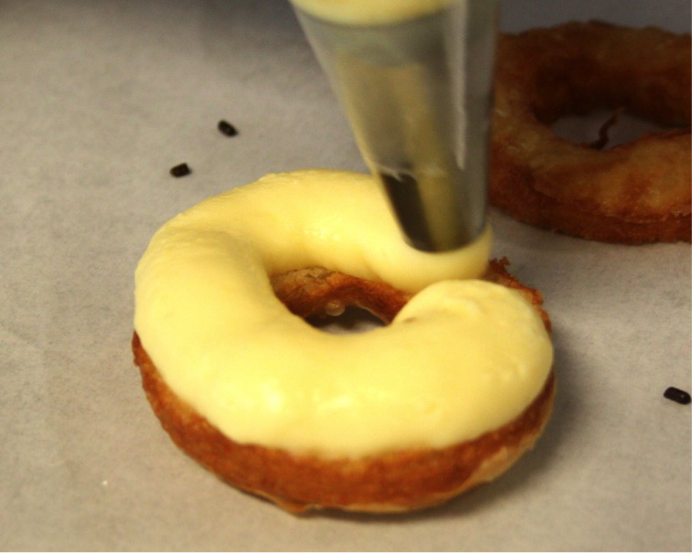 Cronut Being Iced with Yellow Icing