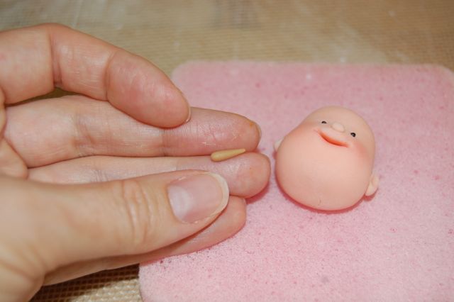 Hand Holding Small Roll of Fondant in Fingers
