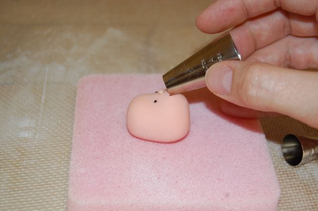 Hand Using Icing Tip to Shape Mouth on Fondant Face
