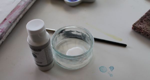 Glass Container with masking fluid, beside paint brush