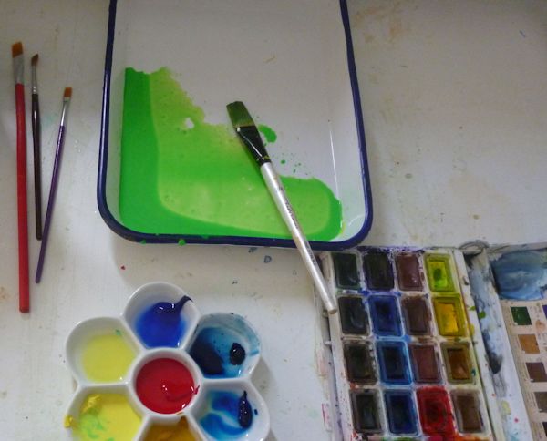 Watercolor pans and palette in process of mixing paints