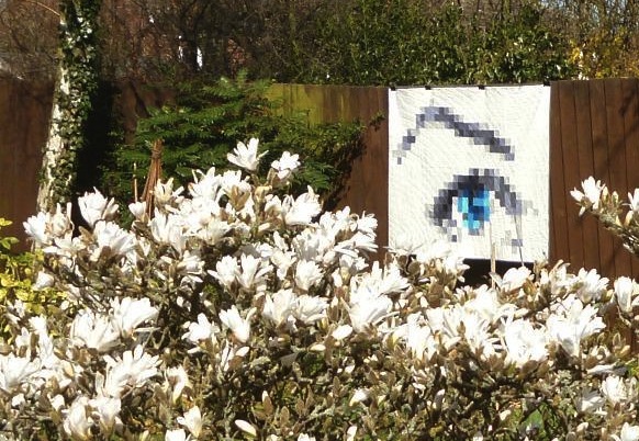 Pixel Quilt Hanging Against Fence