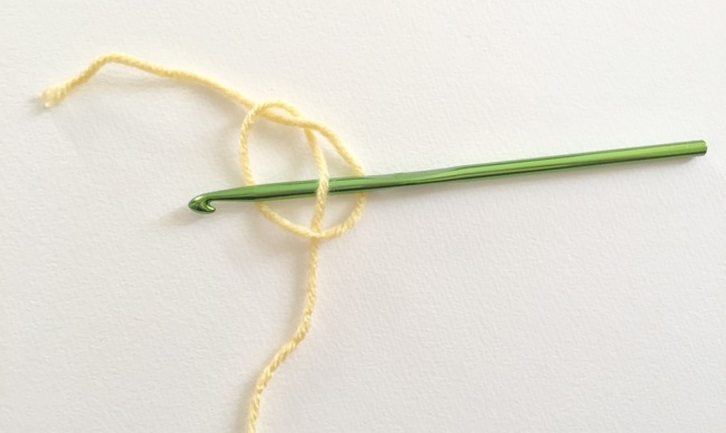 Trozo de hilo amarillo anudado con gancho verde
