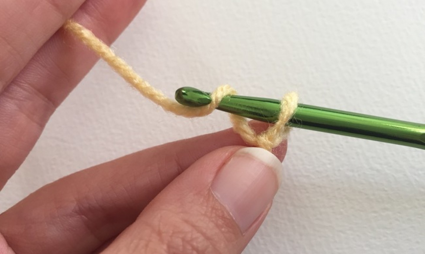 Mano de mujer sosteniendo hilo amarillo anudado