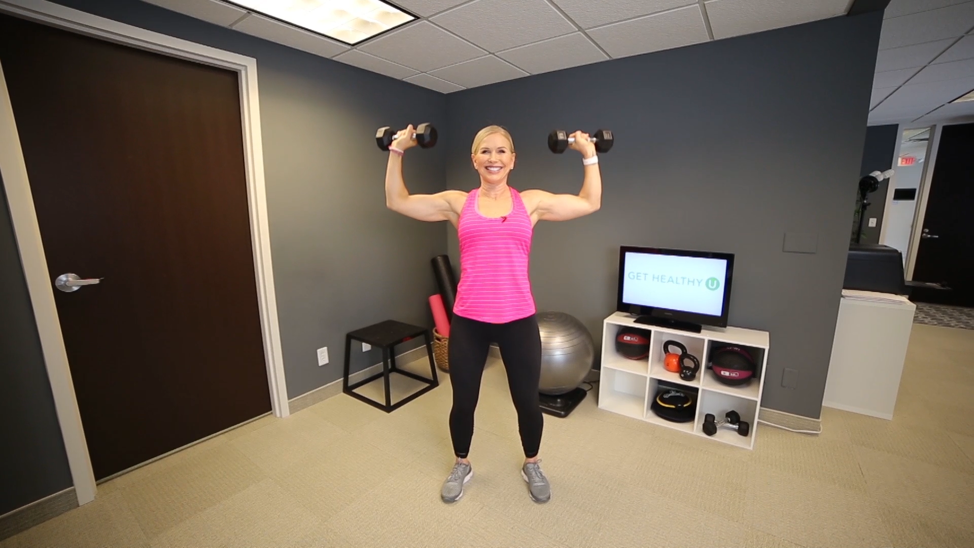Woman in a pink shirt lifting dumbbells