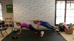 Two women working out in front of a white brick wall