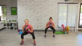 Two women doing squats with medicine balls