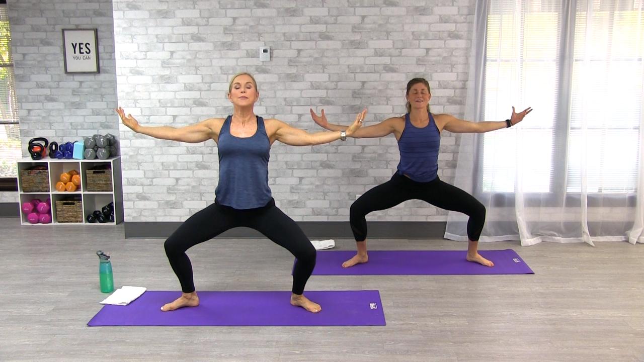 Two women doing yoga on purple mats